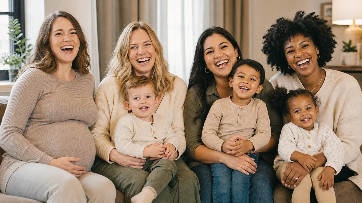 Four diverse mothers and three young children smiling together at home